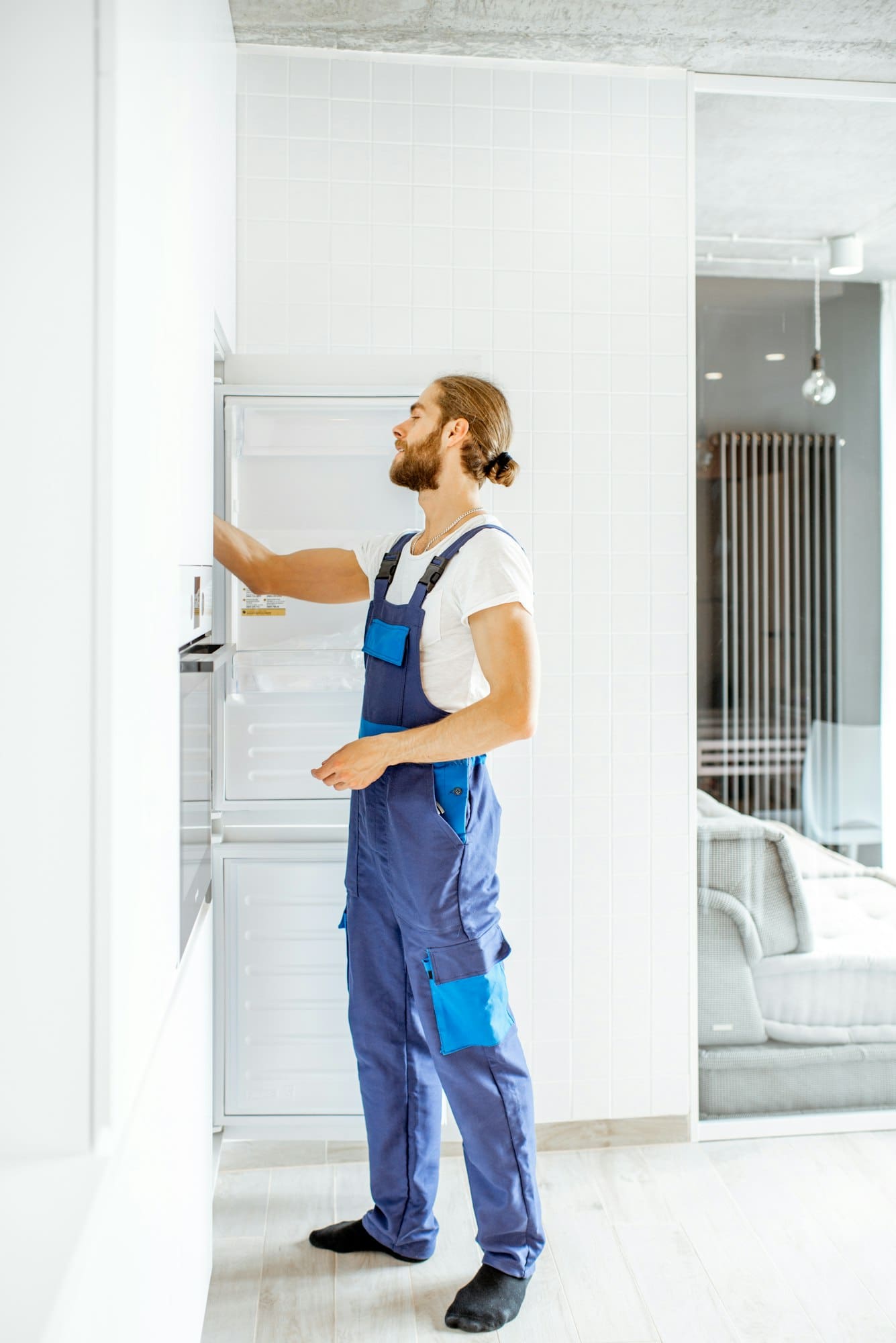 Workman installing fridge on the kitchen at home